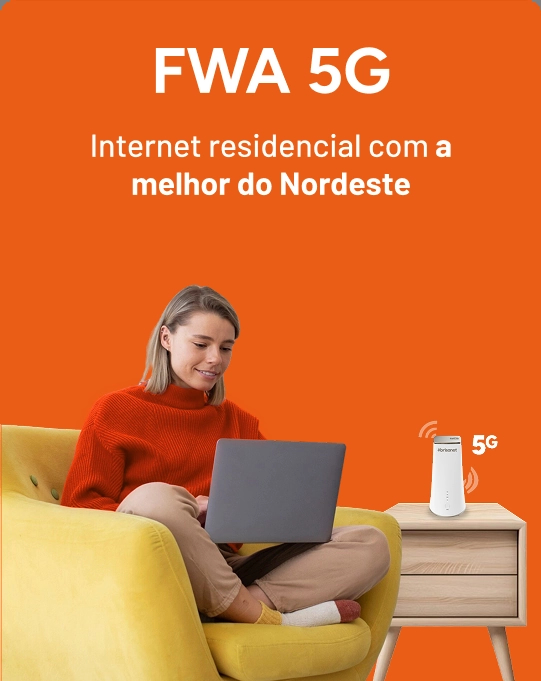Mulher branca de blusa laranja sentada em uma poltrona amarela, usando um notebook, com um roteador FWA 5G sobre uma mesa ao lado.